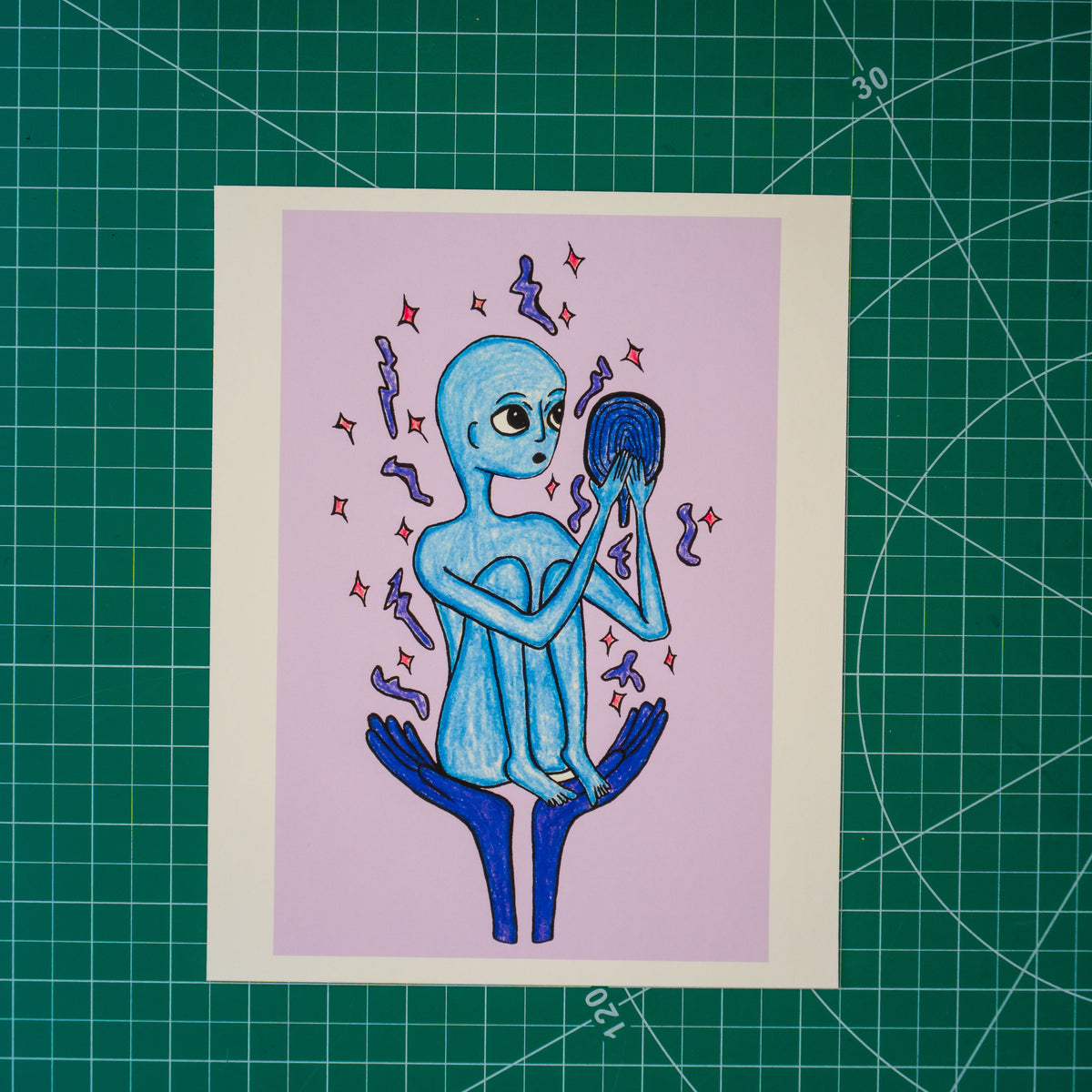A mixed media drawing of an alien-like figure held up in the palms of two hands. Their knees are bunched up to their chest as they look with wonder into a mirror. Surrounding them are stars and dots. 