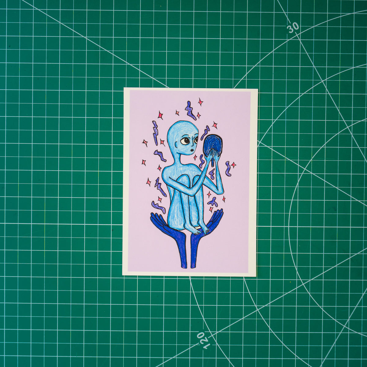 A mixed media drawing of an alien-like figure held up in the palms of two hands. Their knees are bunched up to their chest as they look with wonder into a mirror. Surrounding them are stars and dots. 