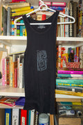 A black sleeveless tank top with a stylized gray linocut print on the front, hanging on a white plastic hanger in front of a bookshelf filled with books.