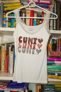 A white sleeveless tank top with "cunt <3" linocut print in shades of red and black across the chest, hanging on a white hanger in front of a bookshelf.