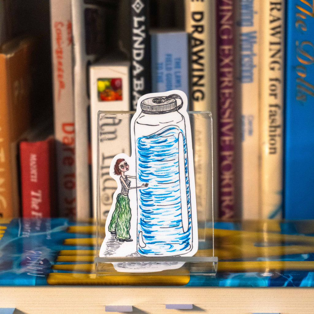 A small die-cut sticker featuring an illustrated figure hugging a waterbottle that is twice her size displayed on a clear acrylic stand in front of a bookshelf.