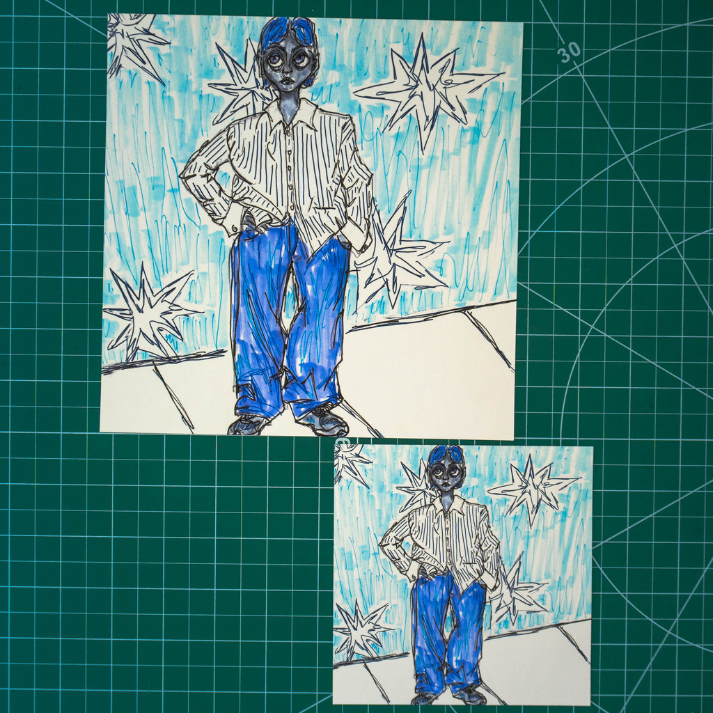 Two art prints on a green cutting mat in different sizes. They both depict a masculine-presenting person in a striped shirt, jeans, and sneakers. They have a mullet haircut and they stand with their hand on their hip, bunching up their shirt. The background behind them is embellished with large stars. 